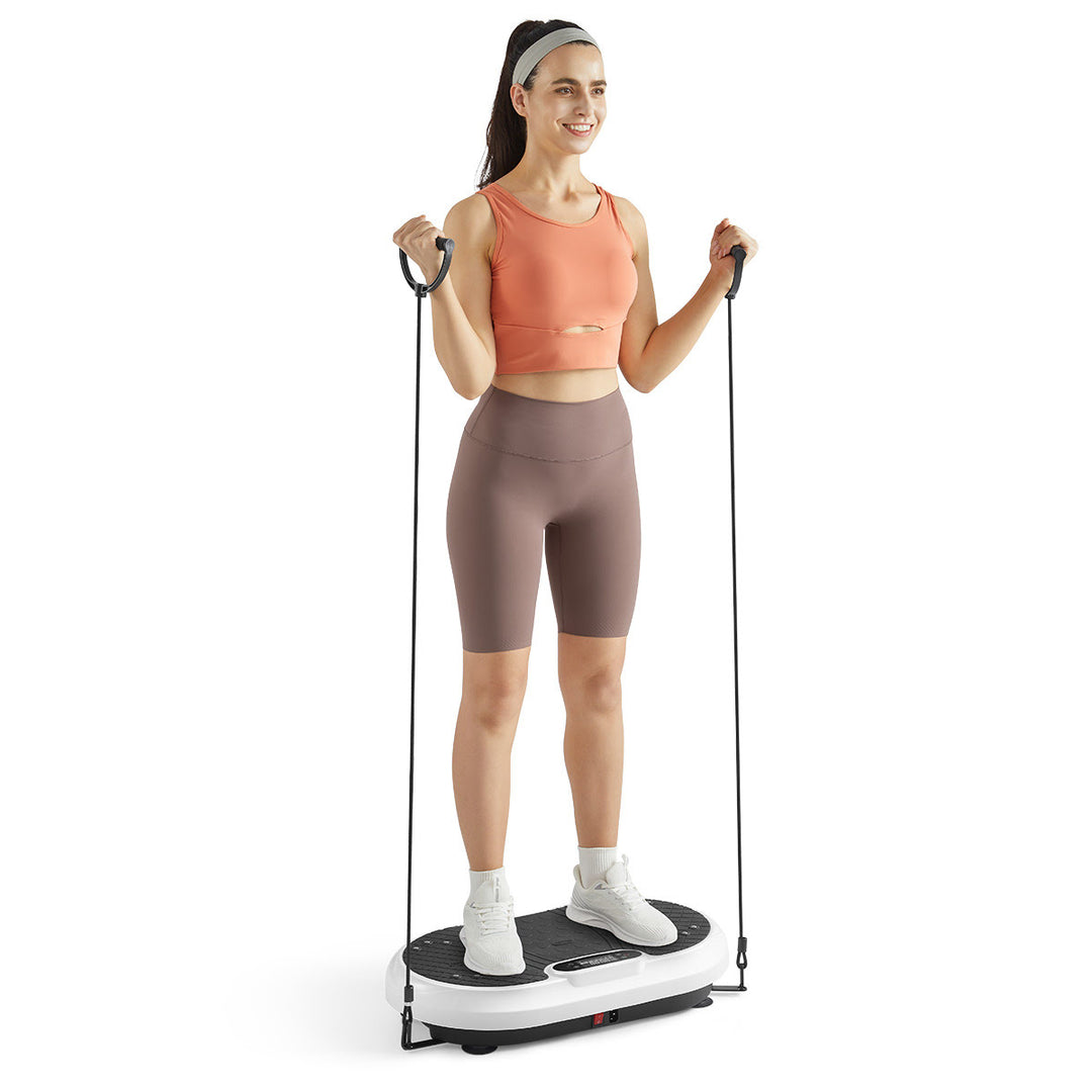Woman performing curls on vibration plate with included exercise bands.