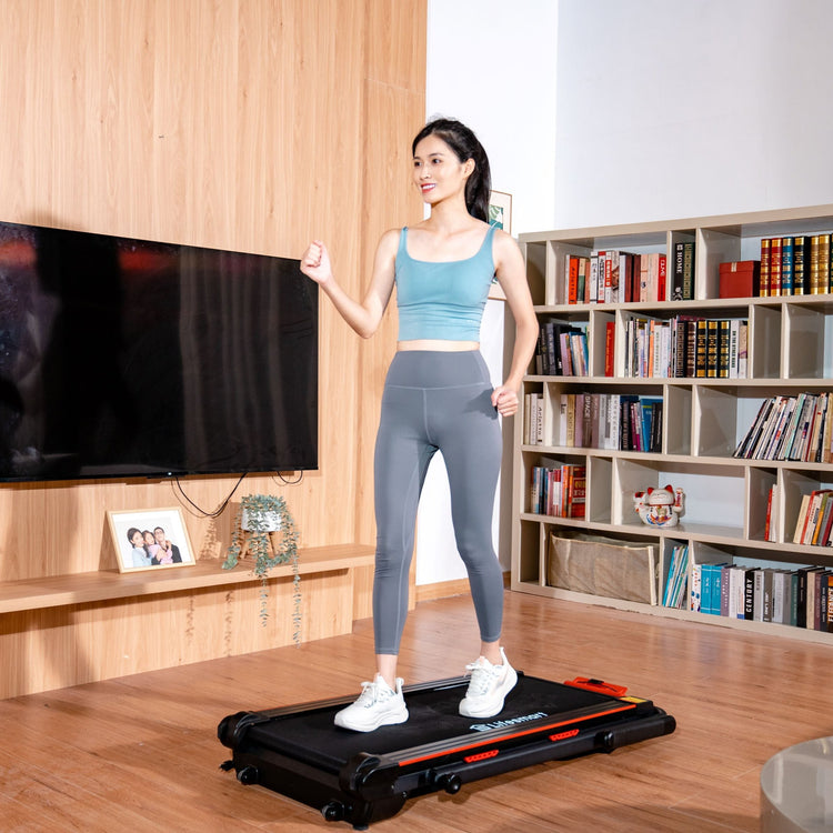 Woman in workout clothes walking on the TM2305 2-in-1 treadmill in her home. The treadmill is in walking mode, no handrails. 