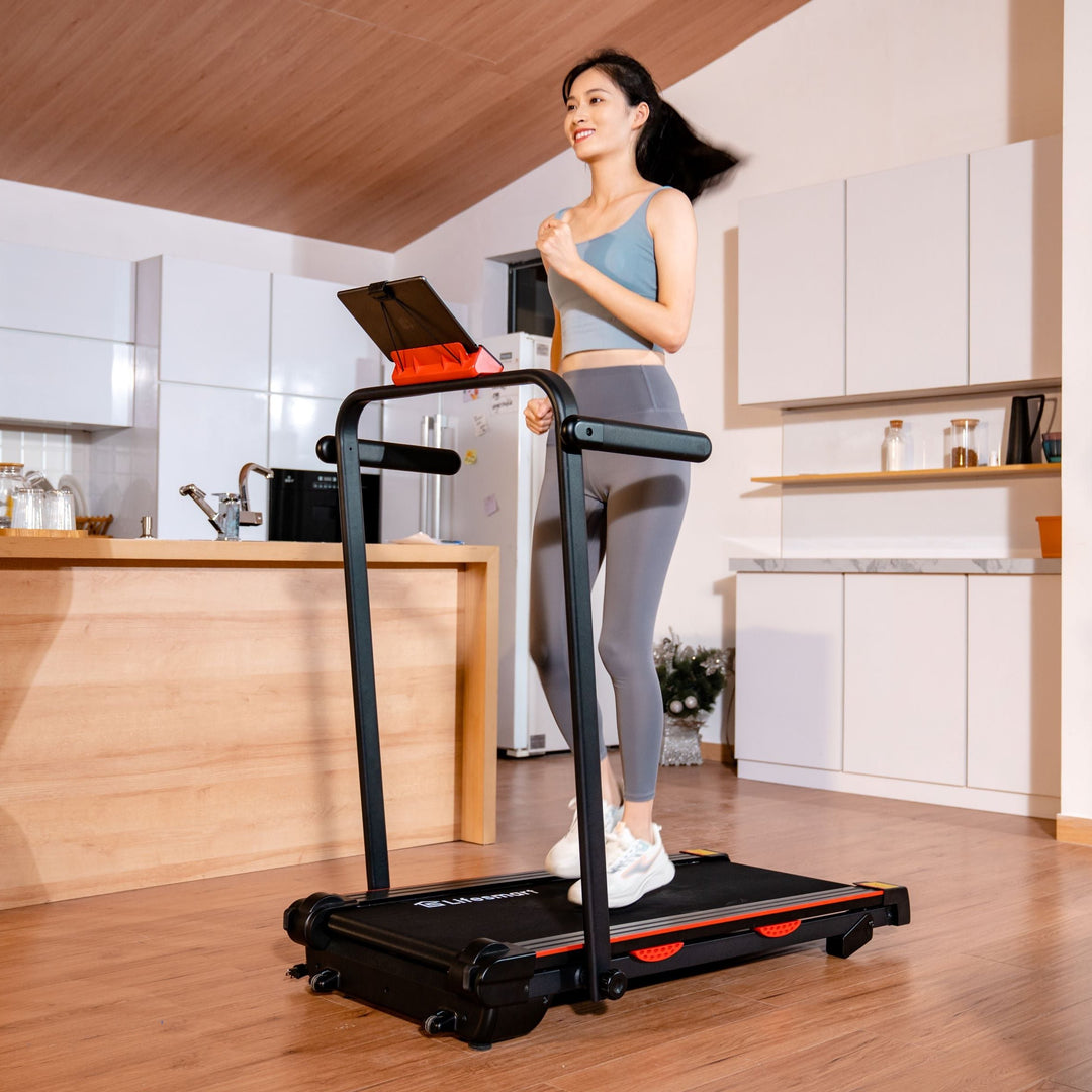 Woman in workout clothes jogging on the TM2305 2-in-1 treadmill in her home. The treadmill is in running mode, with handrails attached. 