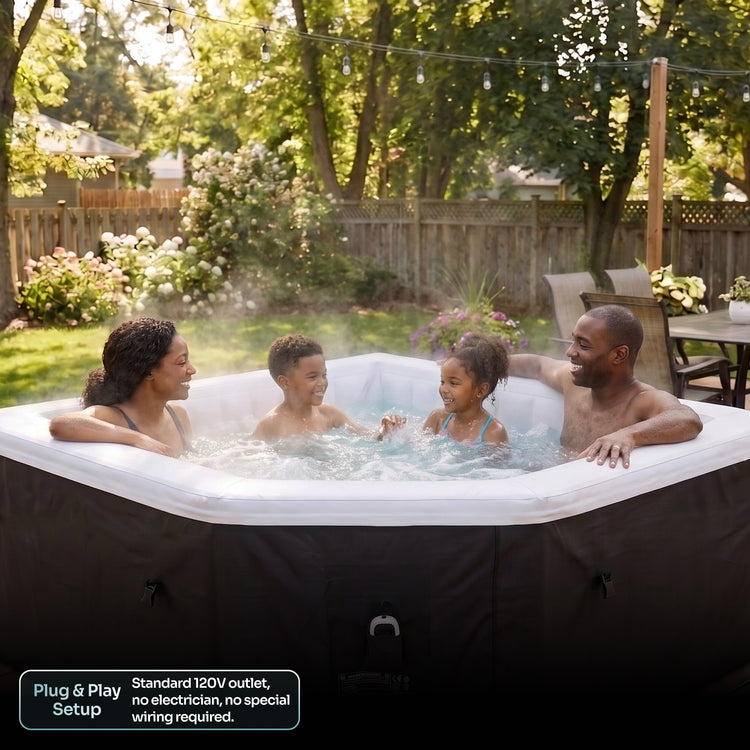 A family of four enjoys a hot spring outdoor tub in a backyard setting. The tub has a black exterior cover and a white interior, with bubbling water creating a misty atmosphere.