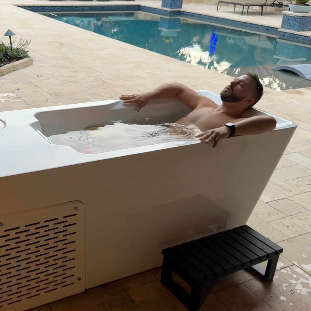 Man relaxing in a hot and cold tub by a pool