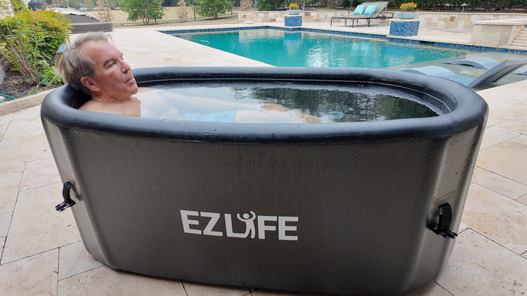 Man recovering inside cold plunge with EZLIFE logo in outdoor setting near pool.