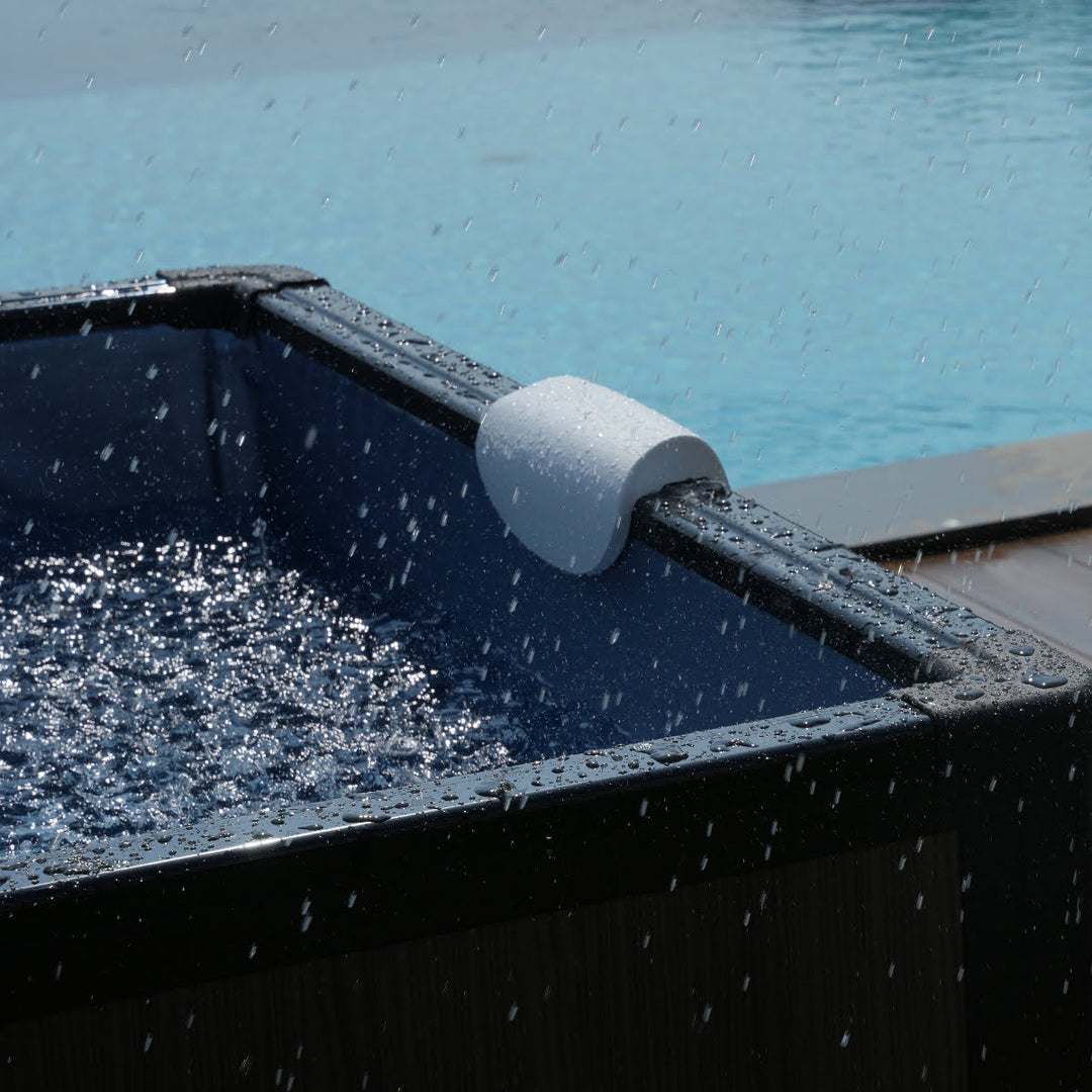 Close up of head rest on side of spa. Water droplets splashing on outside from rain.
