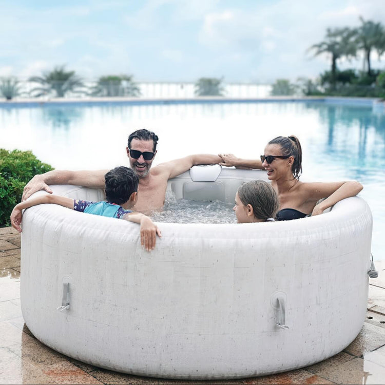 Family of four enjoying a hot tub by a pool with palm trees in the background