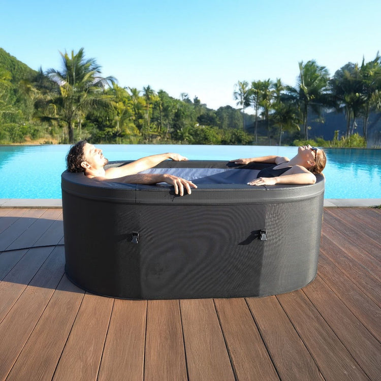 A couple relaxing inside of spa. Surrounding imagery is next to a pool and greenery and palm trees.