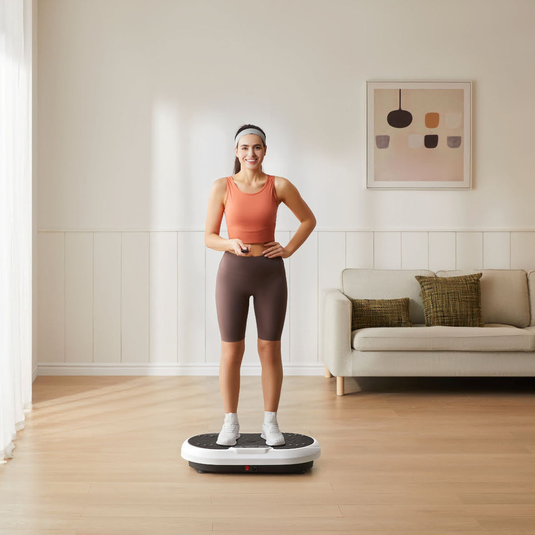 Woman smiling while standing on vibration plate platform with remote in hand.