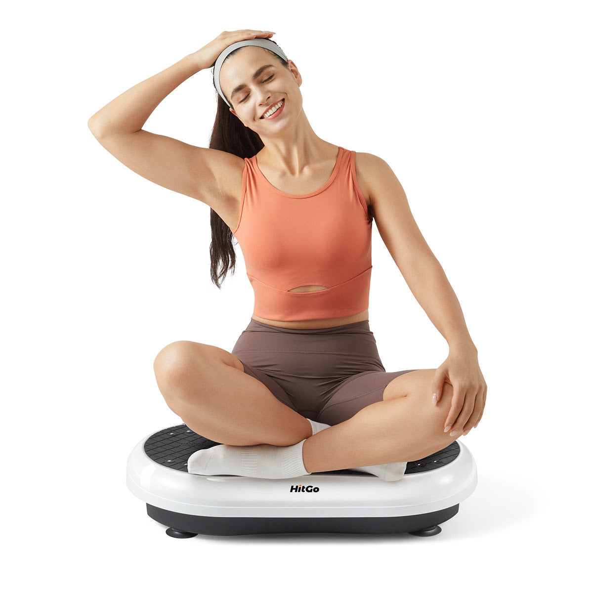 Woman sitting crosslegged on vibration plate performing a neck stretch.