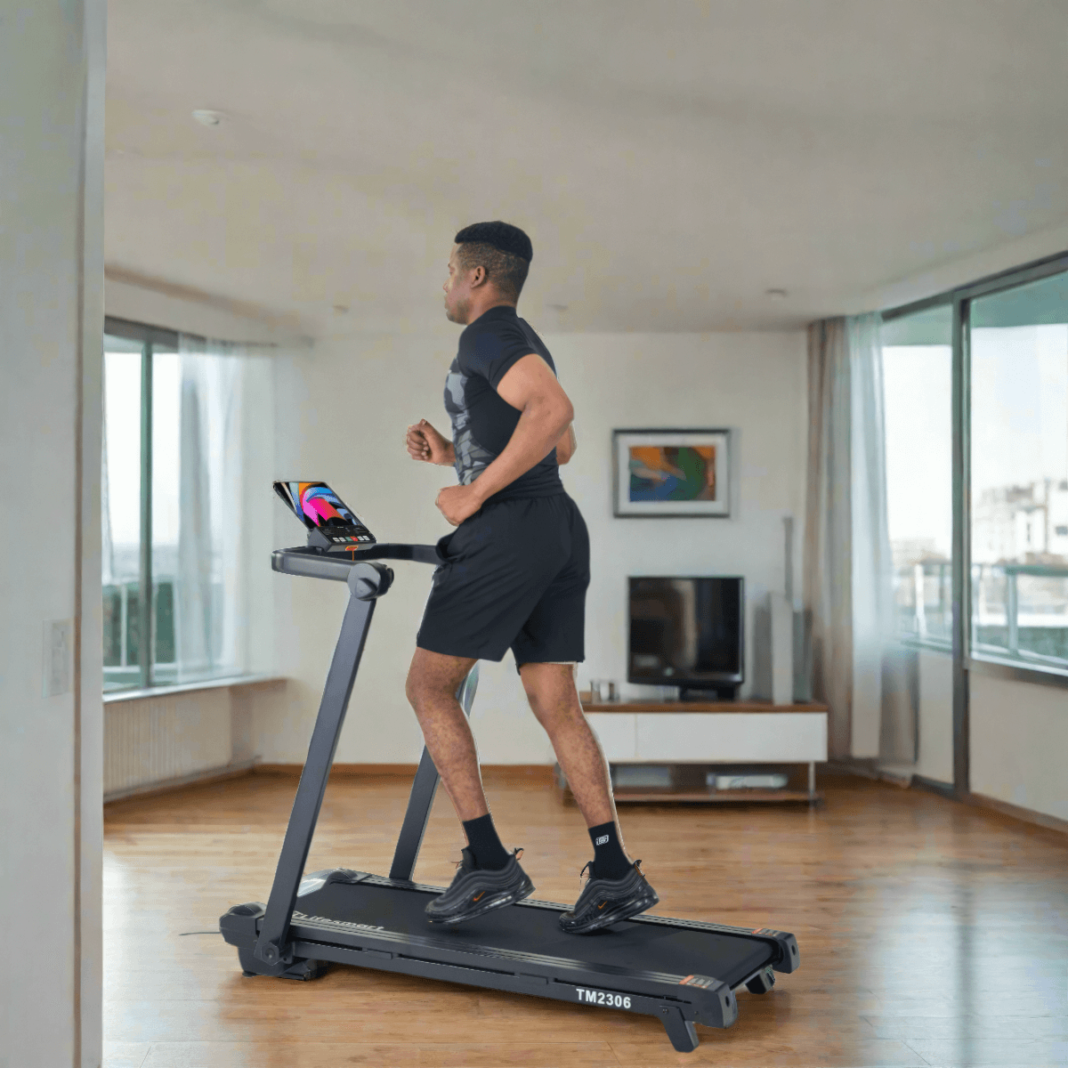Man running on treadmill inside home with tablet on console area.