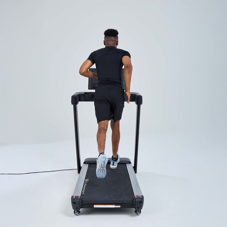 Man running on treadmill. Image angled behind treadmill.