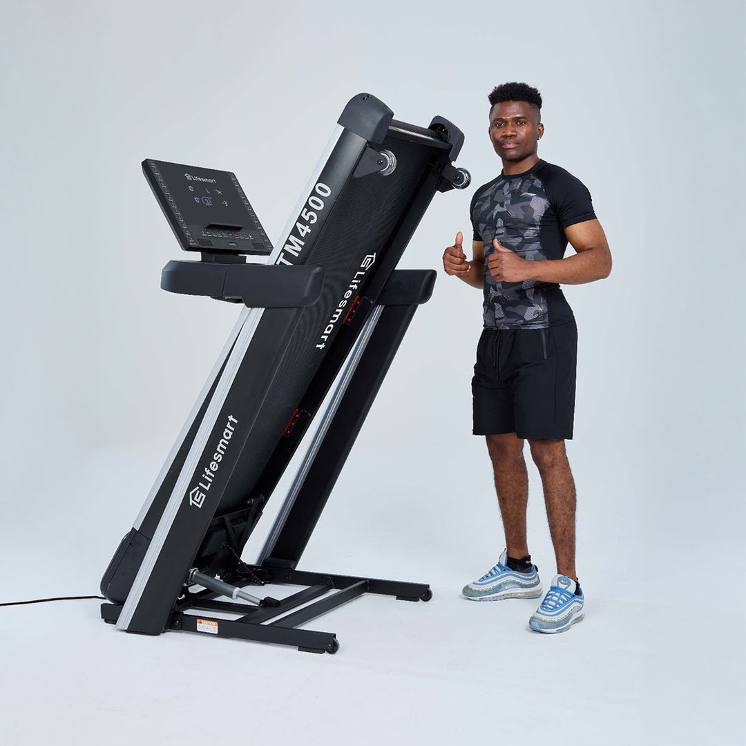 Man standing next to treadmill in storage mode after pressing the Power Touch button. Man giving thumbs up.