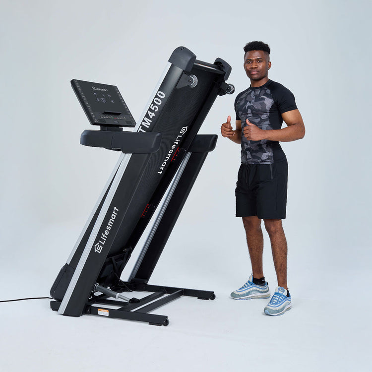 Man standing next to treadmill in storage mode after pressing the Power Touch button. Man giving thumbs up.