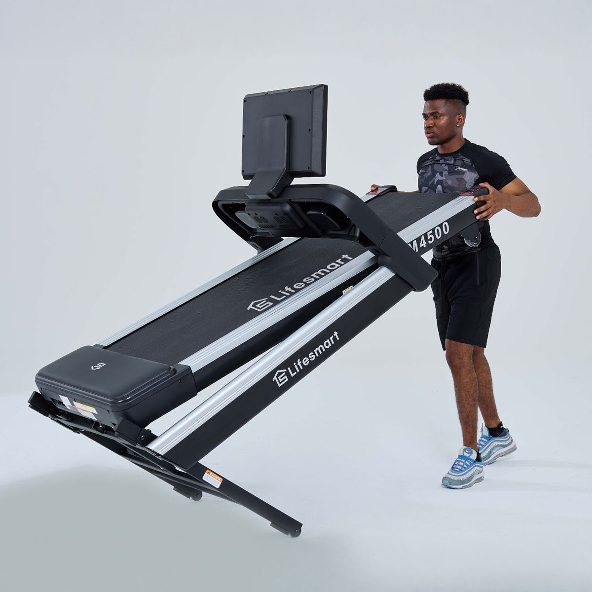 Treadmill is folded and tilted, being moved by a man.