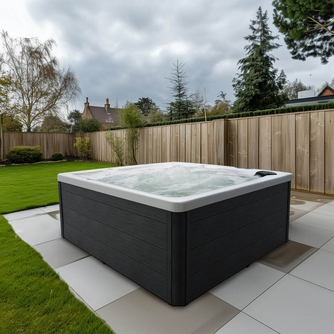 Outdoor backyard patio with spa placed on tiles. Spa has bubbling water.