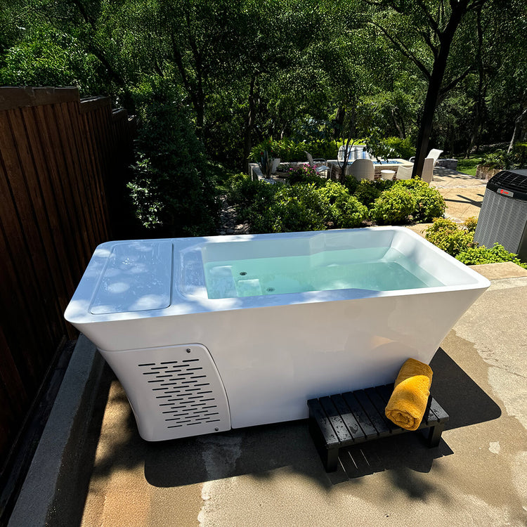 Alta cold plunge in outdoor patio setting with water filled inside the tub and a towel folded up outside the Alta cold plunge.