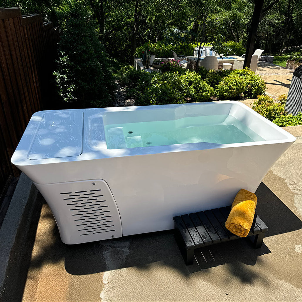Alta cold plunge in outdoor patio setting with water filled inside the tub and a towel folded up outside the Alta cold plunge.
