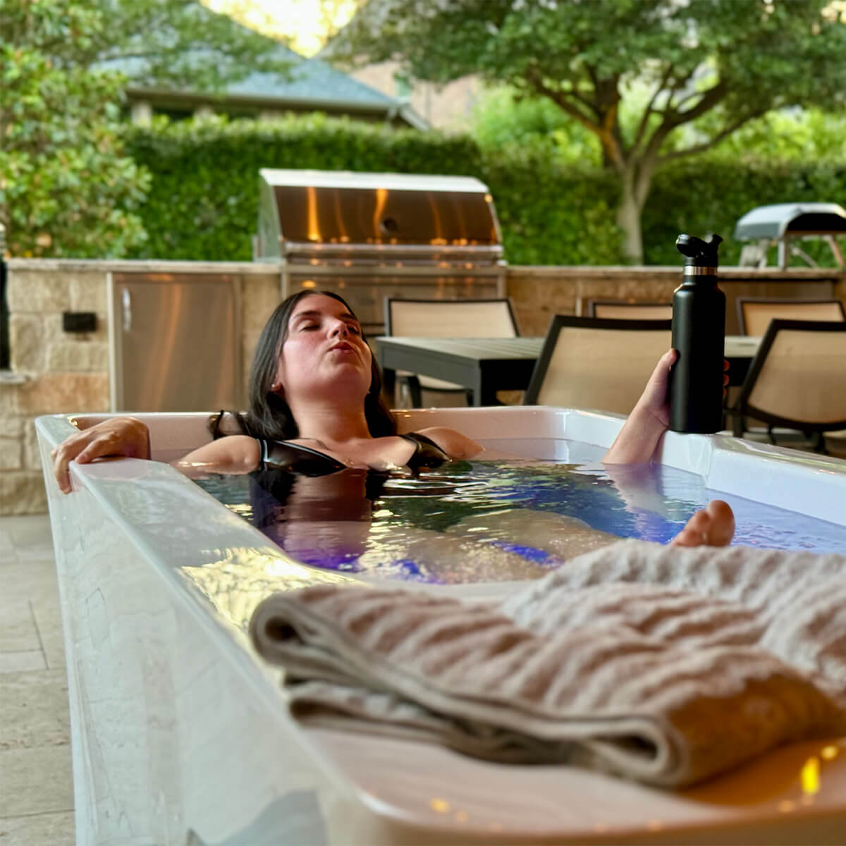 Woman in LifeTrend Alta cold plunge ice bath on patio setting.