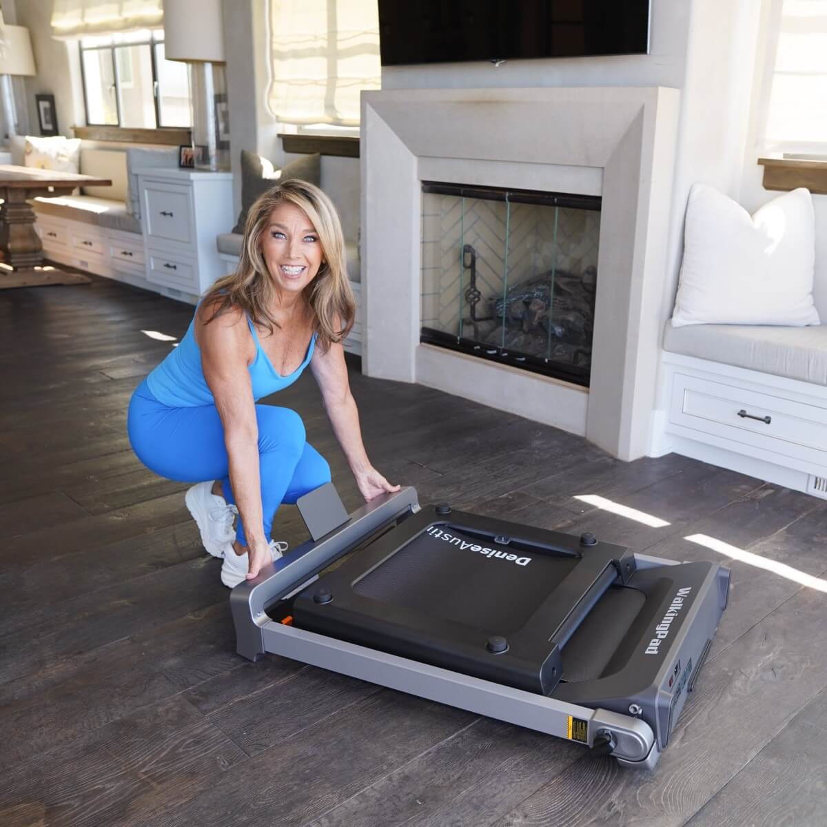 Denise Austin setting the WalkingPad treadmill into storage mode.