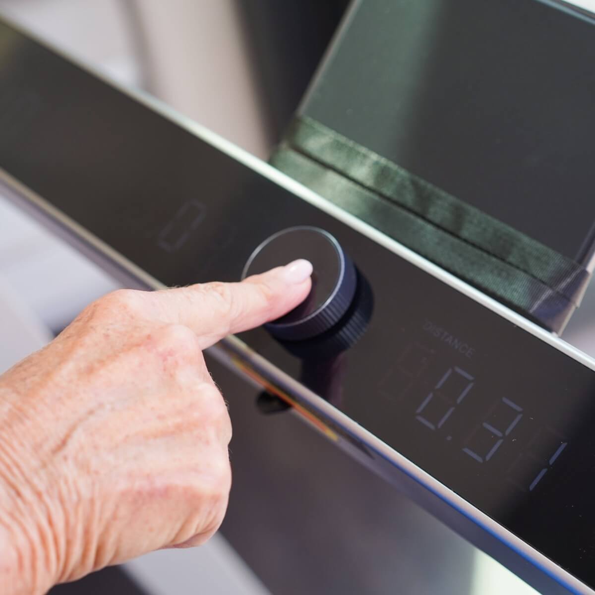 A finger pressing the speed dial on the console of the treadmill.